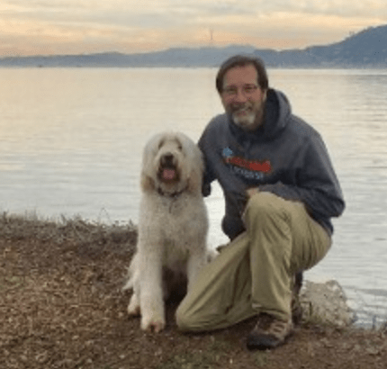 labradoodle with man kneeling by lake